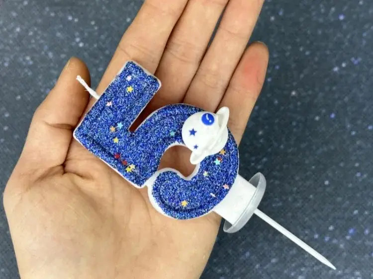 Una vela azul con brillo con el número cinco para cumpleaños, con una figura de astronauta blanca en la parte superior y decoraciones de estrellas en una barra de cera blanca, para vela de cumpleaños numeral temática del espacio, fiesta planetaria, adorno para pastel.