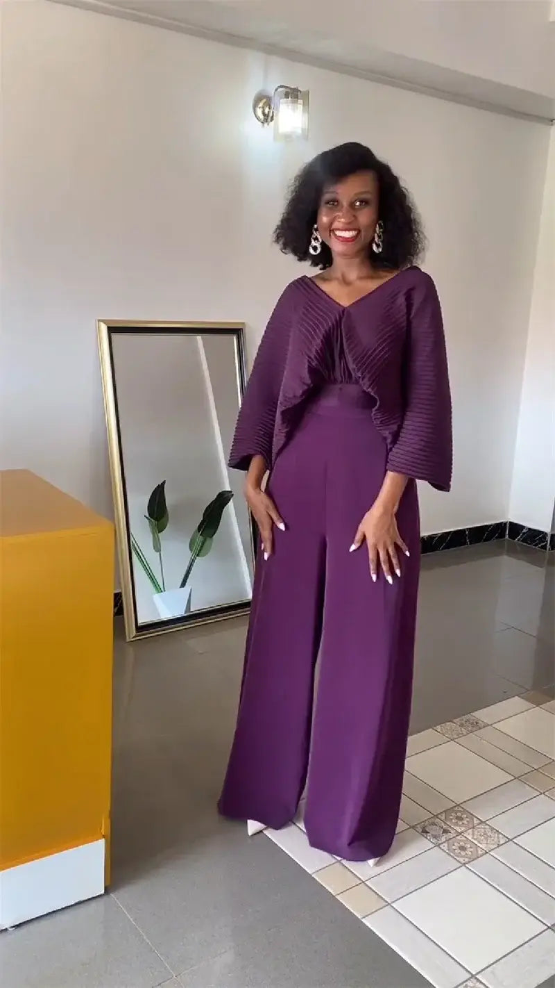 A woman wearing a vibrant purple satin two-piece set with ruffled detailing on the top and wide-leg pants.