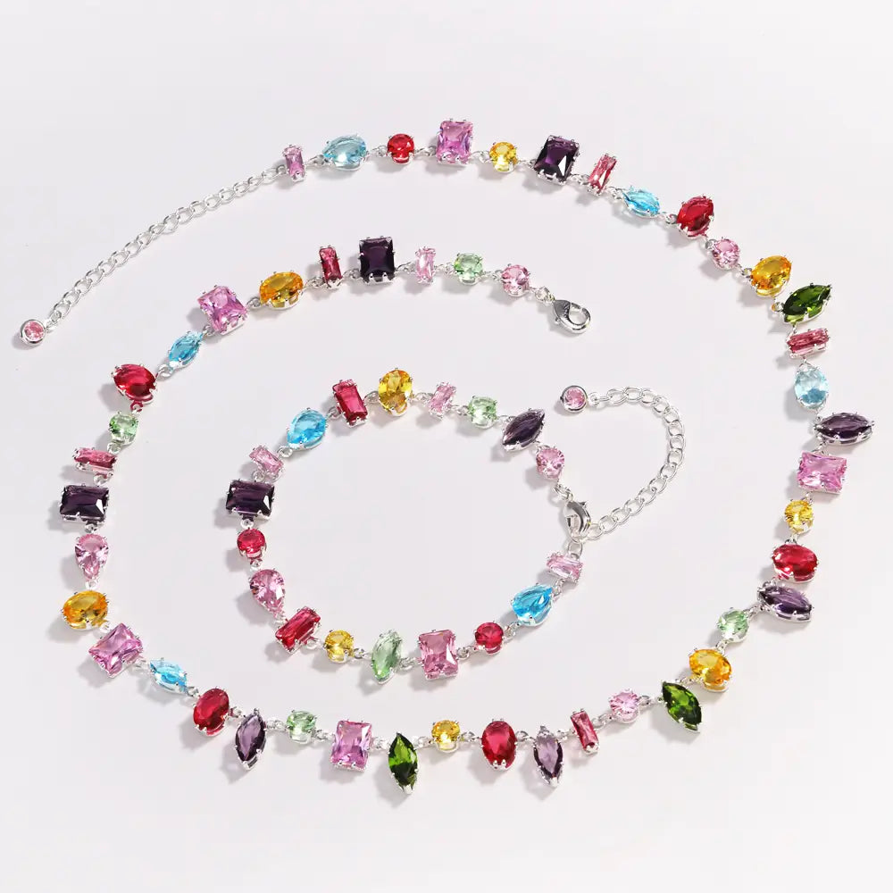 A colorful zircon crystal gold plated necklace and matching bracelet set featuring a silver chain with vibrant multi-colored stones in pink red blue yellow green and purple cuts.