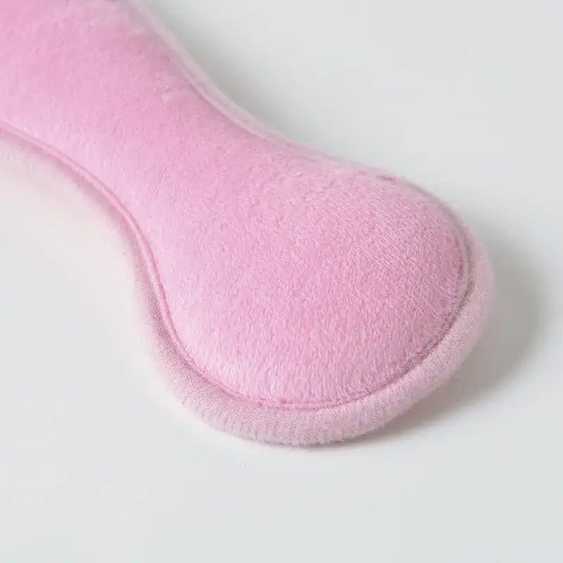 Rosafarbene plüschige knochenförmige Handwärmer-Vorrichtung, gestaltet als Schlafhilfe für den Kopfstützenriemen eines Baby-Kindersitzes für Komfort und Wärme.