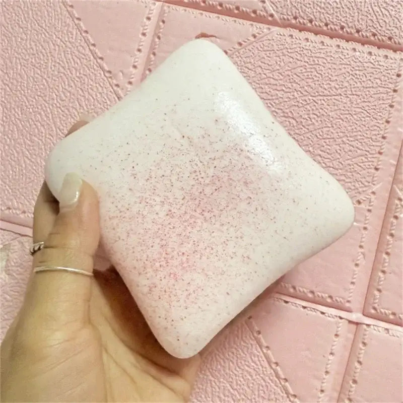 Jouet anti-stress en forme de toast moelleux, couleur macaron, blanc cassé tendre, avec une texture tachetée rose discrète et une forme carrée arrondie.