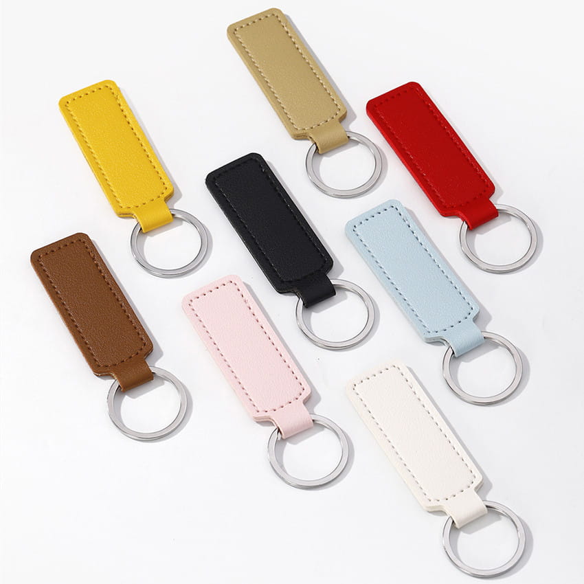 A collection of minimalist rectangular leather car keychains in assorted solid colors including yellow beige red black light blue brown pink and white.