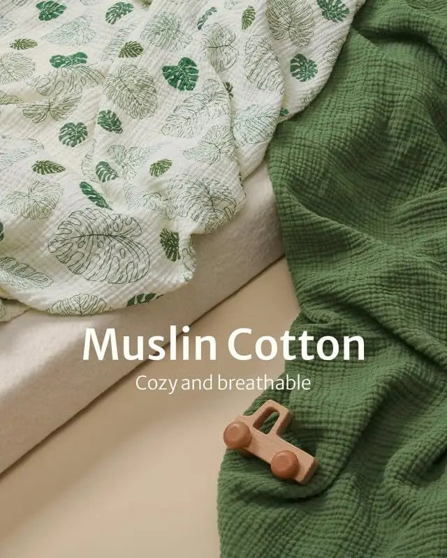 ein weiches, strukturiertes Babybettlaken-Set aus grünem Baumwollmuslin mit einem dezenten Blattmuster.
