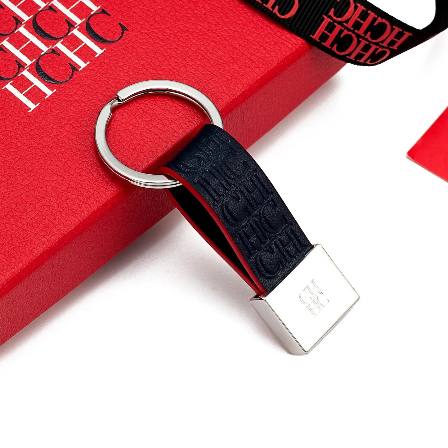 Porta llaves minimalista de cuero texturizado azul marino con anillo metálico plateado y logotipo hchc en relieve, diseñado como accesorio de equipaje.