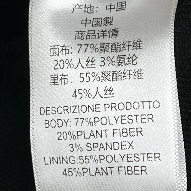 Étiquette blanche d’entretien du tissu avec texte noir indiquant la composition et l’origine à l’intérieur d’une jupe crayon grise taille haute de longueur genou au style Y2K.