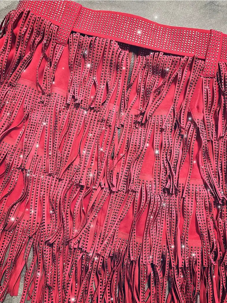 Mini-jupe taille haute rouge suède à franges en strass, avec des strass scintillants le long de la ceinture et des lanières à franges en cascade.