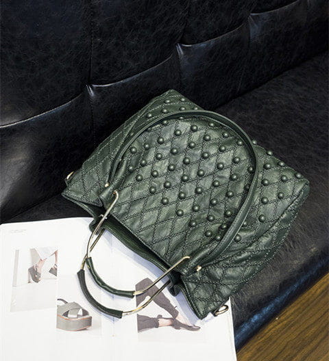 Bolso de hombro de cuero verde oscuro acolchado con herrajes y tachuelas metálicas negras que muestran el compartimento interior.