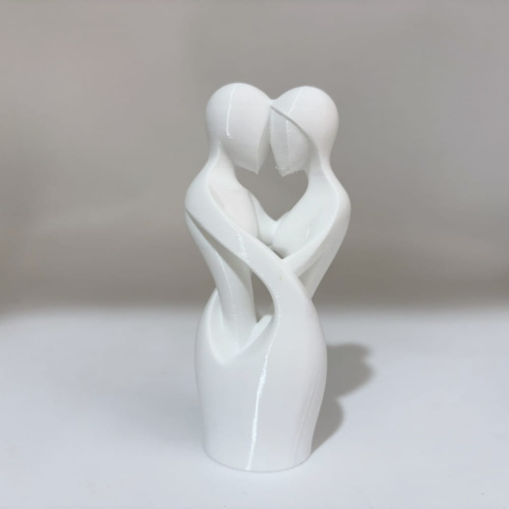 a sleek glossy white ceramic sculpture of two abstract figures embracing to form a heart shape titled intertwined lovers heart sculpture modern decor.