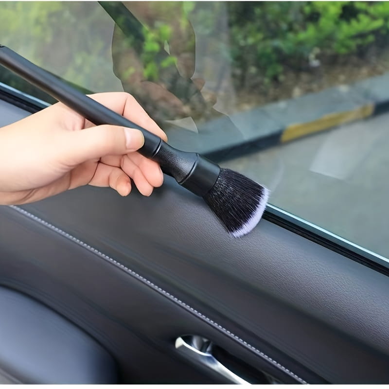 Detailreinigungsbürste für den Innenraum eines schwarzen Fahrzeugs mit weichen Borsten und einem eleganten Griff, dargestellt von der Rückseite.