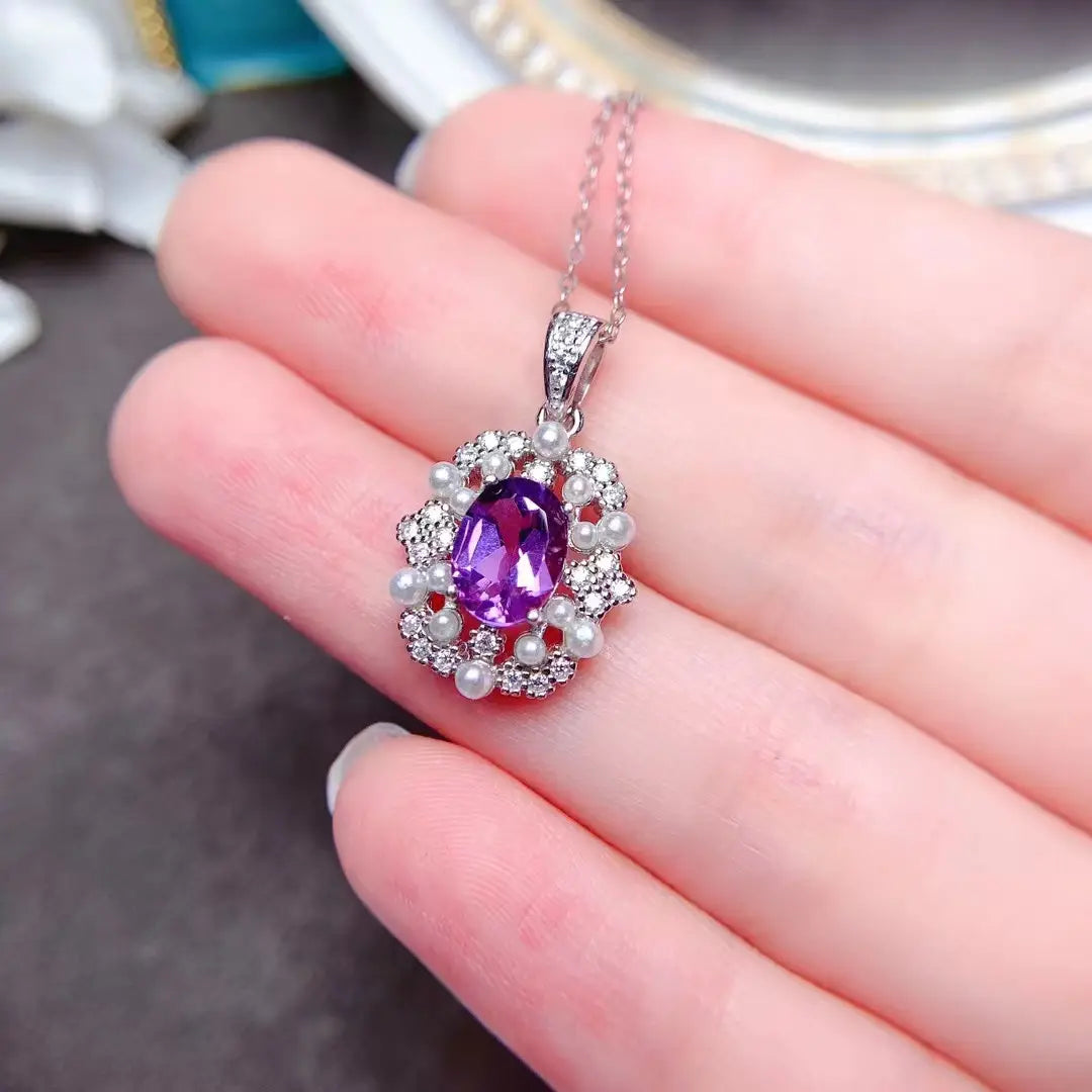 Un pendentif d’ensemble de bijoux en argent sterling avec quartz rose, en argent étincelant, présentant un motif délicat en argent, avec une améthyste ovale au centre entourée de diamants étincelants et de petites perles blanches, suspendue à une chaîne élégante.