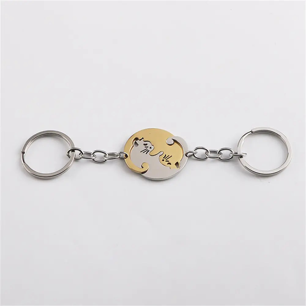 A sleek metallic interlocking cat couple keychain set featuring a circular pendant with two cats in a yin-yang design, one golden and one silver.