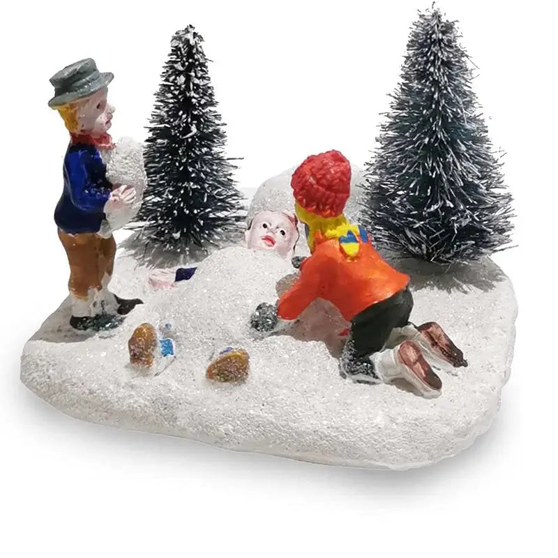 Kinder, die mit Schnee spielen: Weihnachtliches Dorf-Figürchen mit einer Miniatur-Szene beim Schneemannbauen, mit zwei detaillierten Figuren in Winterkleidung und vereisten Tannenbäumen auf einer strukturierten weißen Basis.