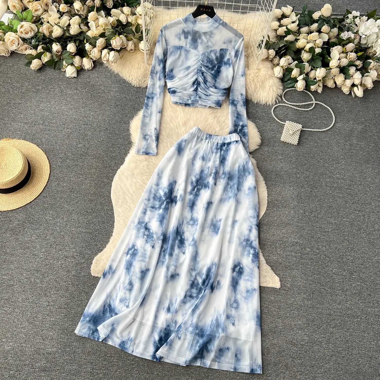 blue and white tie-dye two piece mesh skirt set marble print featuring a sheer long-sleeved top with ruched detailing and a flowing maxi skirt with elastic closure type
