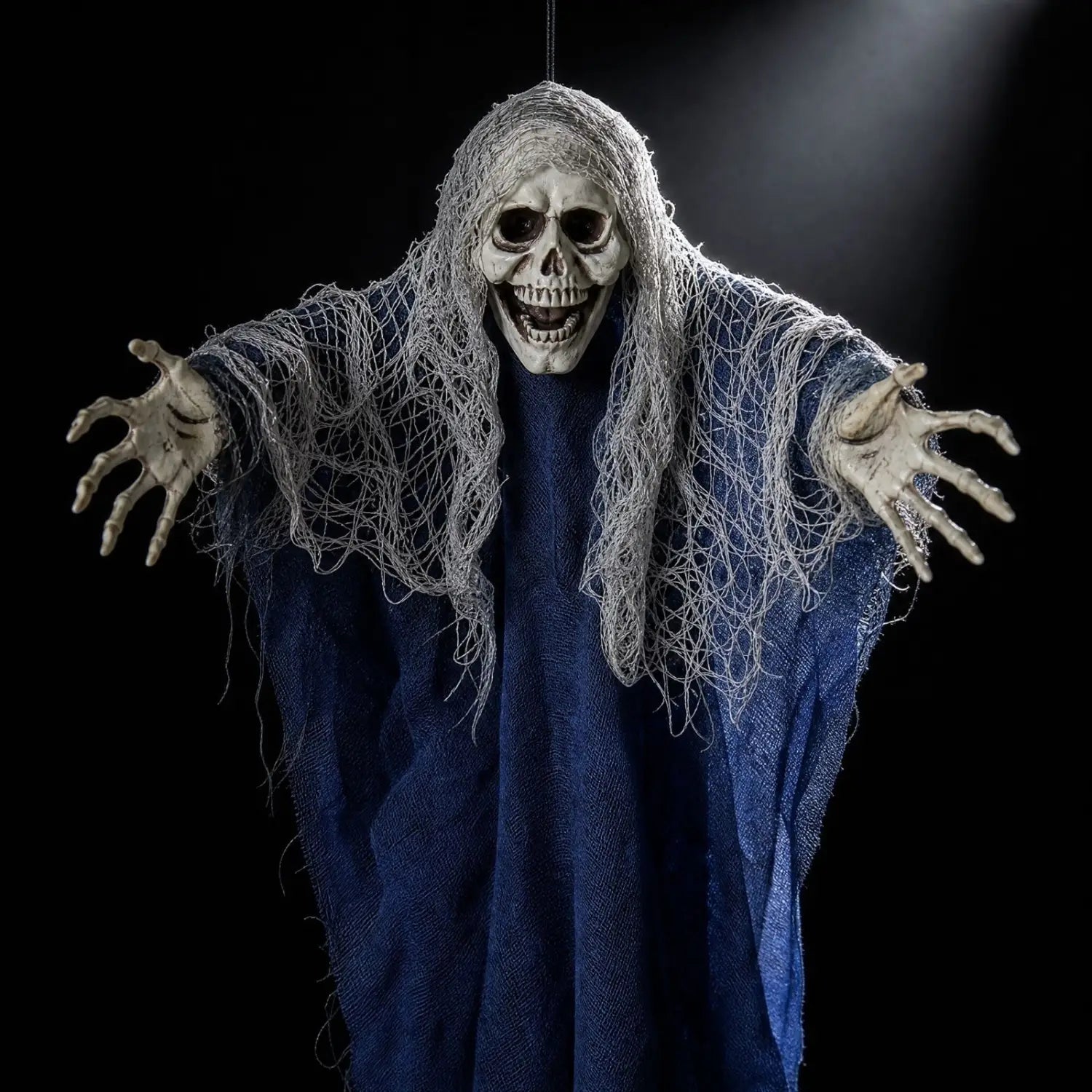 Décoration d’Halloween suspendue en forme de squelette fantôme, accessoire suspendu, présentant une silhouette squelettique effrayante drapée dans une robe en tissu bleu foncé, avec de longs filets gris emmêlés qui tombent sur ses épaules et ses bras.