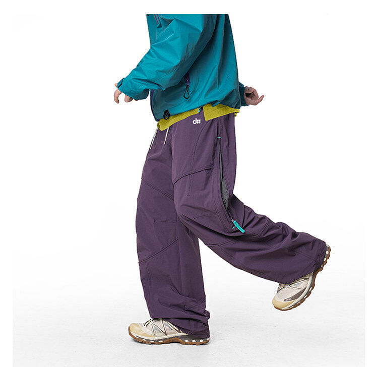 pantalones cargo impermeables de senderismo para hombre en color morado, con detalles de cremallera verde azulado y cinturilla amarilla, elaborados con material de secado rápido.