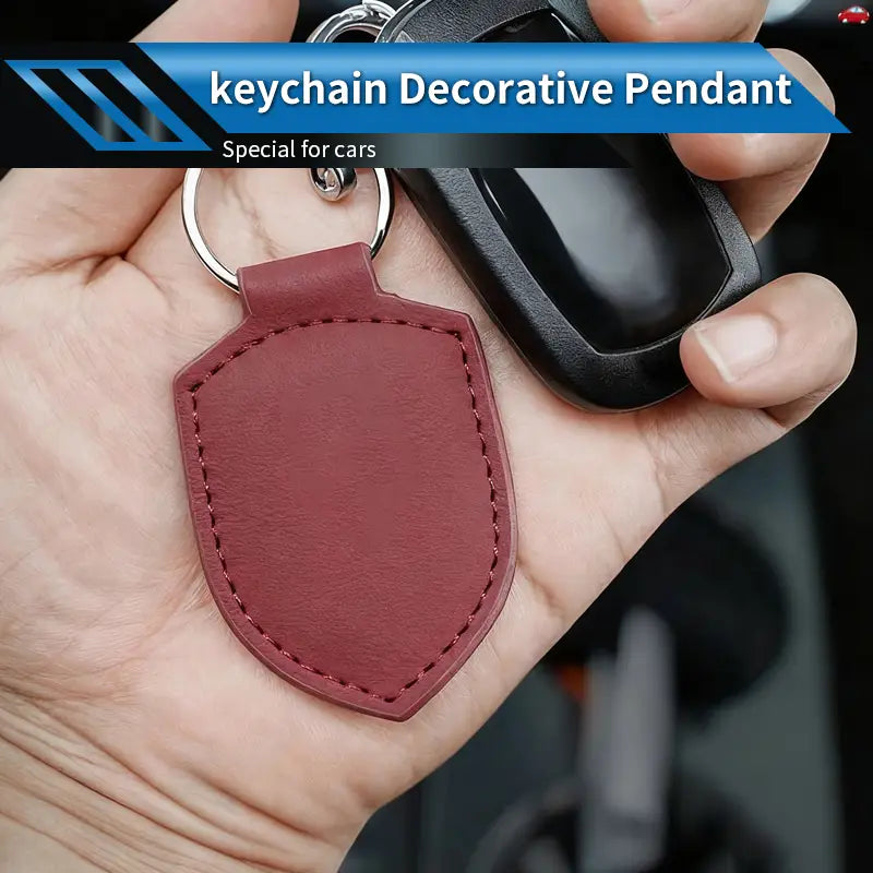 A maroon leather shield-shaped car keychain ring organizer with visible stitching along the edges.