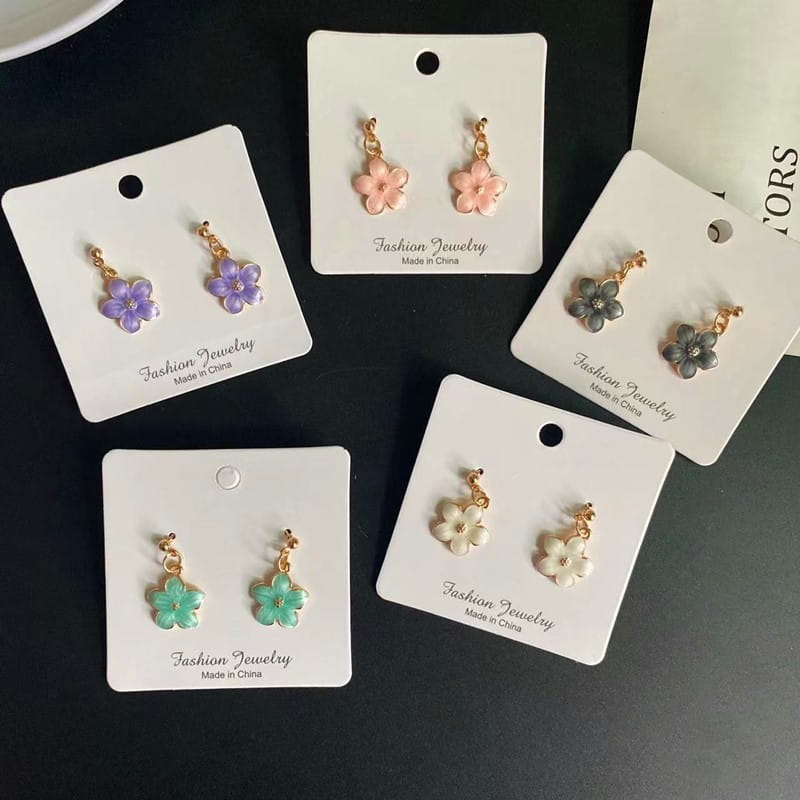 Boucles d’oreilles florales aux couleurs pastel, avec des attaches en métal à l’aspect doré et des pétales émaillés en rose, violet, gris, vert et blanc, complétant un collier pendentif de fleur romantique et mignon avec une chaîne à maillons délicate.
