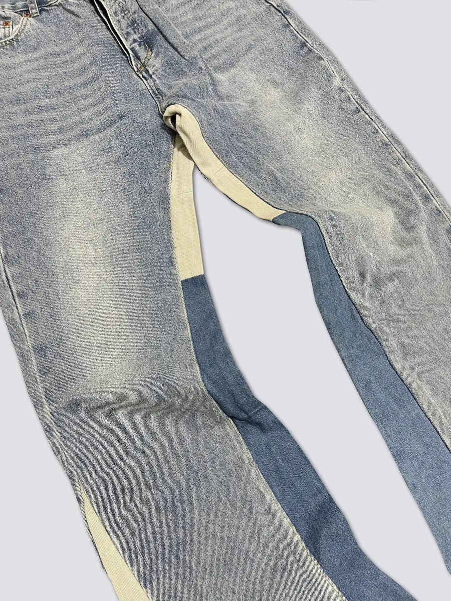 Hell gewaschene Denim-Patchwork-Glockenjeans mit markanten Zweifarben-Akzenten aus Creme und Mittelblau entlang der äußeren Bein-Nähte.