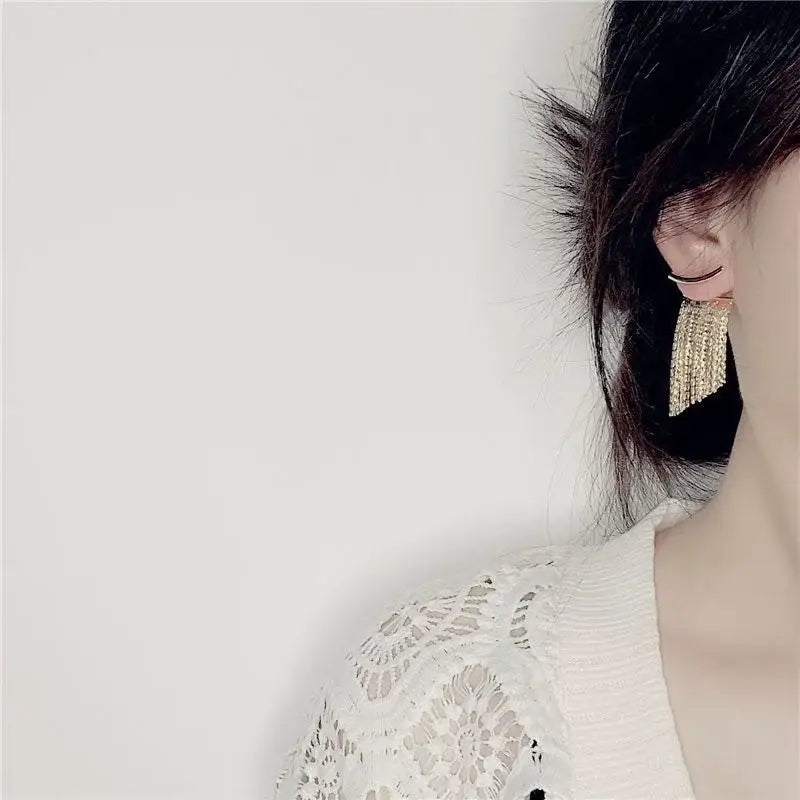 Boucles d’oreilles déclaration à frange ton or, avec une cascade de petites cristaux étincelants.