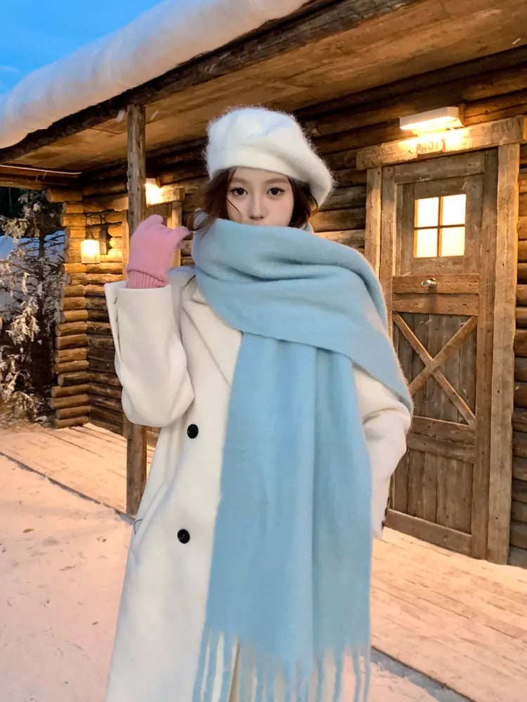 Una bufanda de cachemir de invierno rosa para mujer con una textura de lana azul claro suave y una delicada decoración de flecos.