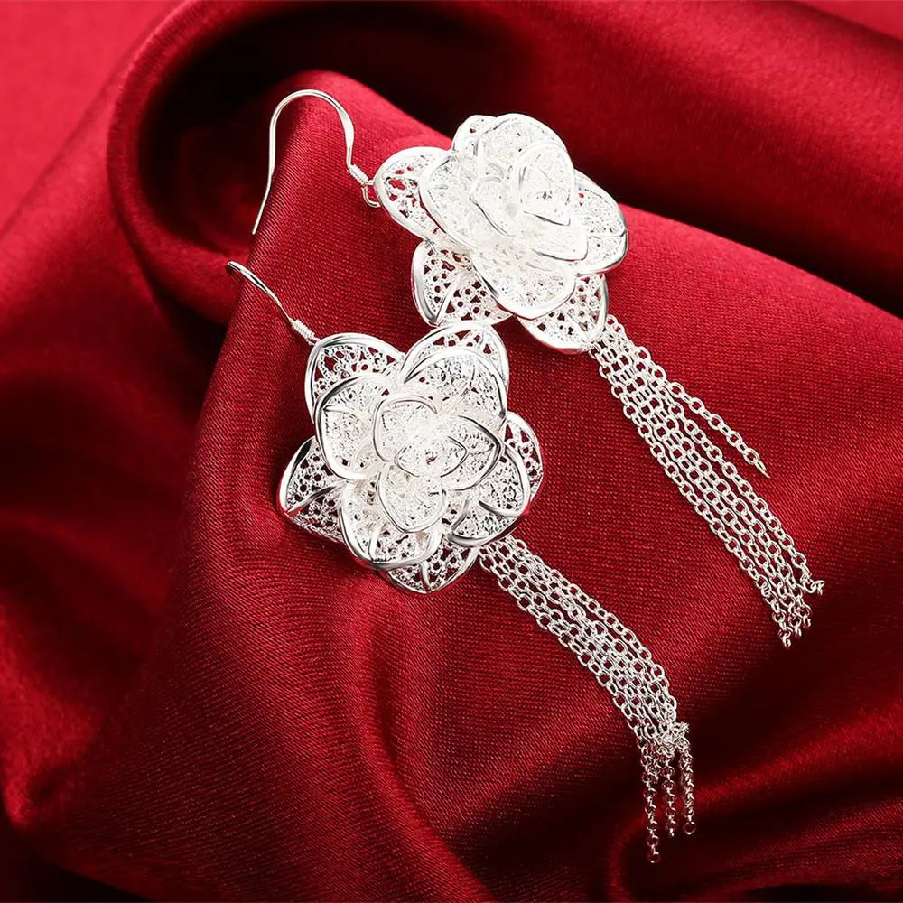 Boucles d’oreilles florales en argent sterling présentant un motif de filigrane complexe avec des glands en chaîne délicats, faisant partie d’un ensemble de bijoux.