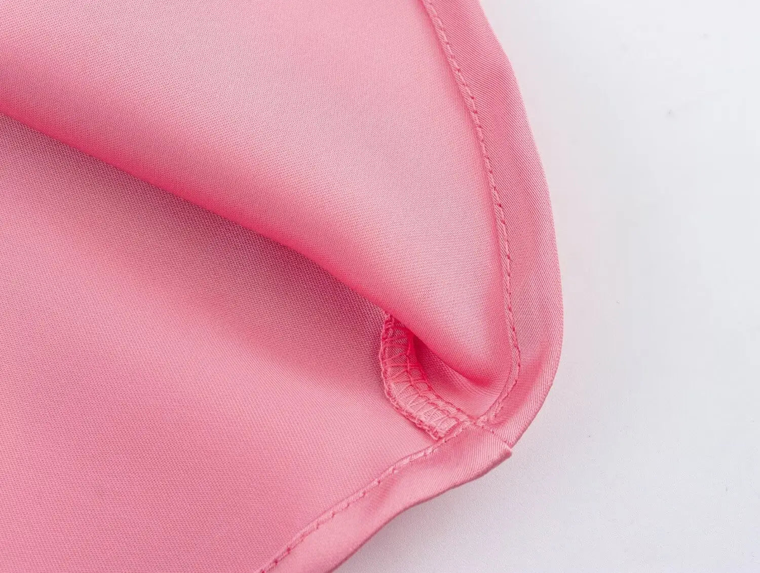 Jupe midi en satin rose tendre à taille haute, bords cousus avec soin, présentant une texture lisse et brillante.