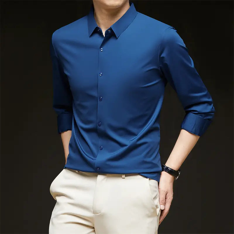 Una camisa de vestir para hombre sin arrugas color azul real elegante, con mangas largas, parte delantera abotonada, cuello impecable y puños enrollados con esmero.