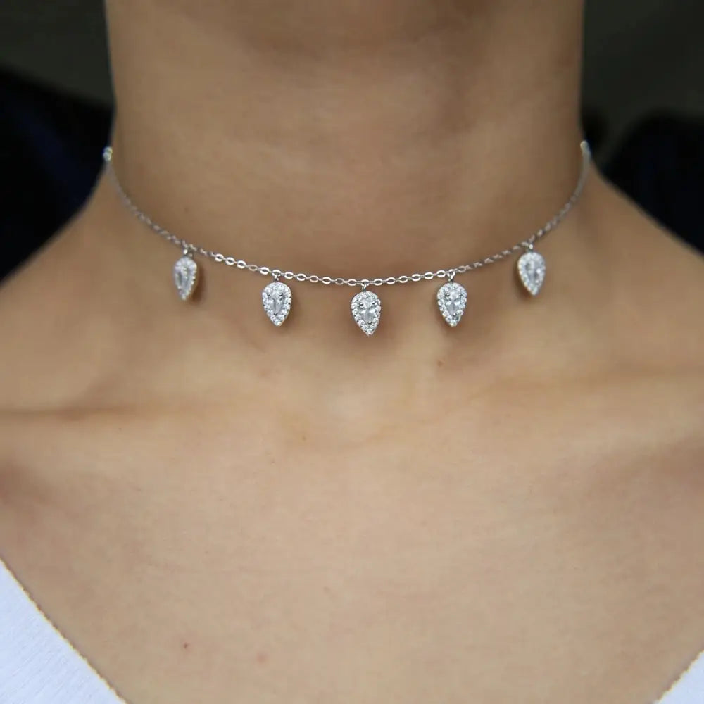 Collar tipo gargantilla con cadena plateada delicada, adornado con cinco colgantes con forma de gota de lágrima, engarzados con cristales cz transparentes brillantes.