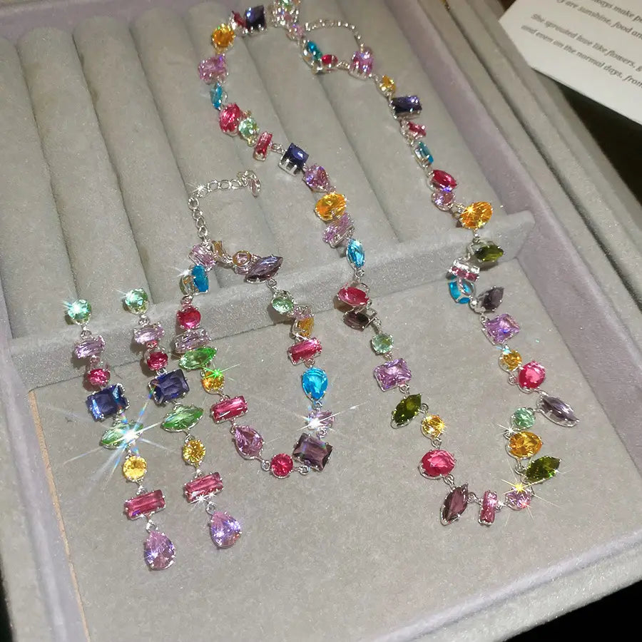 A vibrant multi-colored zircon crystal necklace and matching earrings set in silver-toned metal.