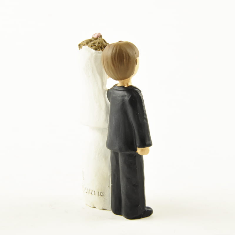 figurine de marié au costume noir se tenant à côté d’une figurine en résine de jeune fille de première communion drapée de blanc, aux cheveux bruns et coiffure florale, pour décoration de table