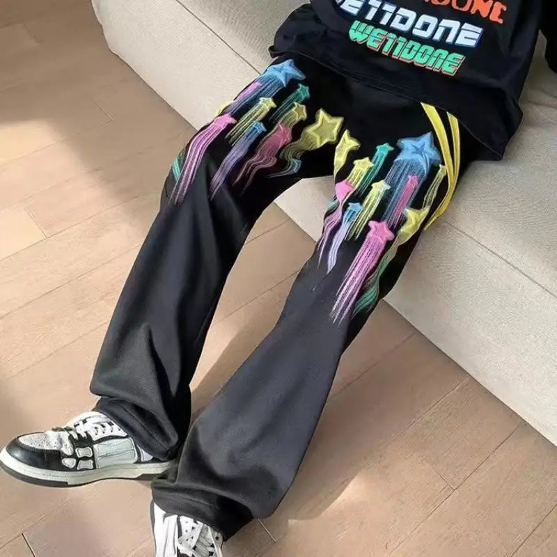 Black wide-leg men sweatpants featuring a vibrant rainbow-colored star and arrow graphic design on the front.