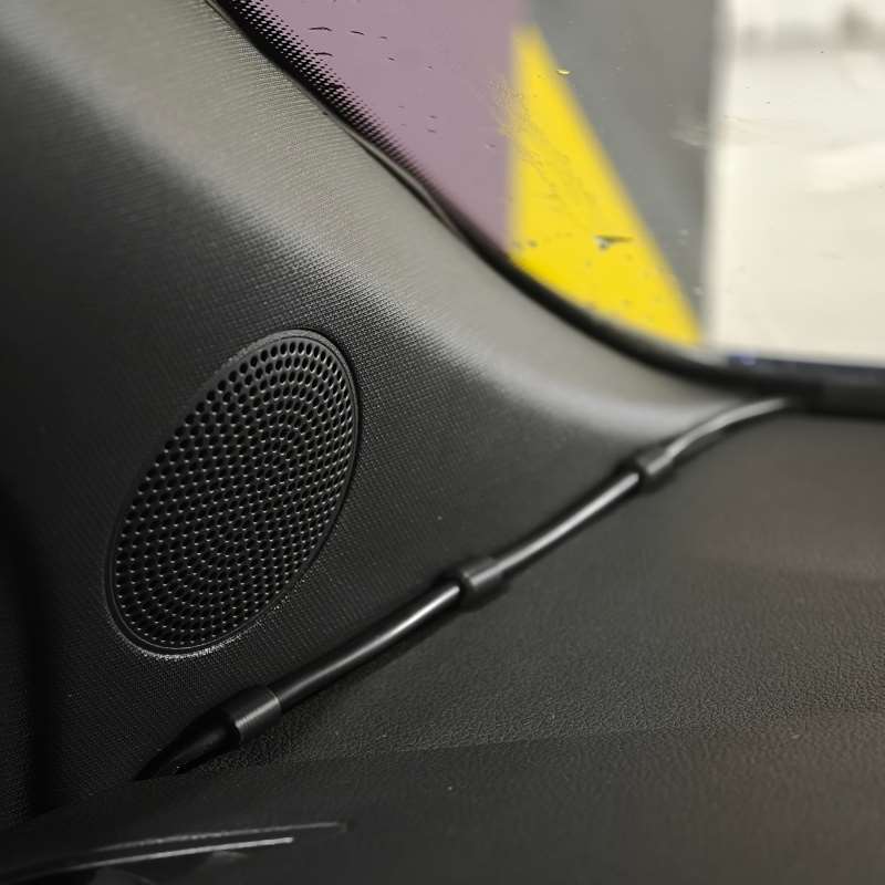 grille d’enceinte de voiture noire texturée pour tableau de bord, avec un motif de perforations circulaires, illustrée avec des pinces de câble pour tableau de bord de voiture à emboîtement s’emboîtant l’une dans l’autre, montées sur le tableau de bord.