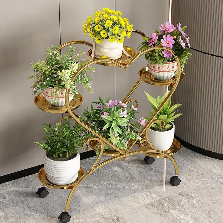 Blumenständer aus goldfarbenem Metall mit Herzdesign und vier Ebenen, auf denen verschiedene Keramiktöpfe auf Rollrädern zur Präsentation von Blumentöpfen stehen.