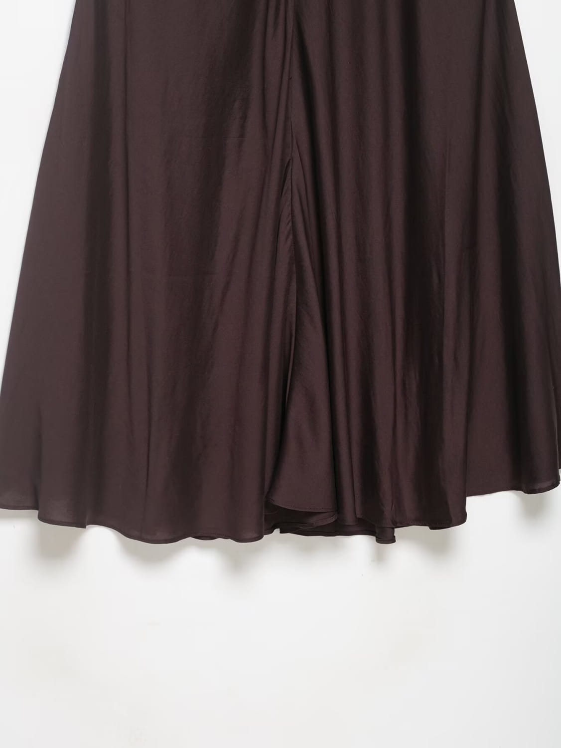 Ein fließender dunkelbrauner Satin-Plisseerock im Midi-Format mit hoher Taille und einem glatten Finish des Stoffes.