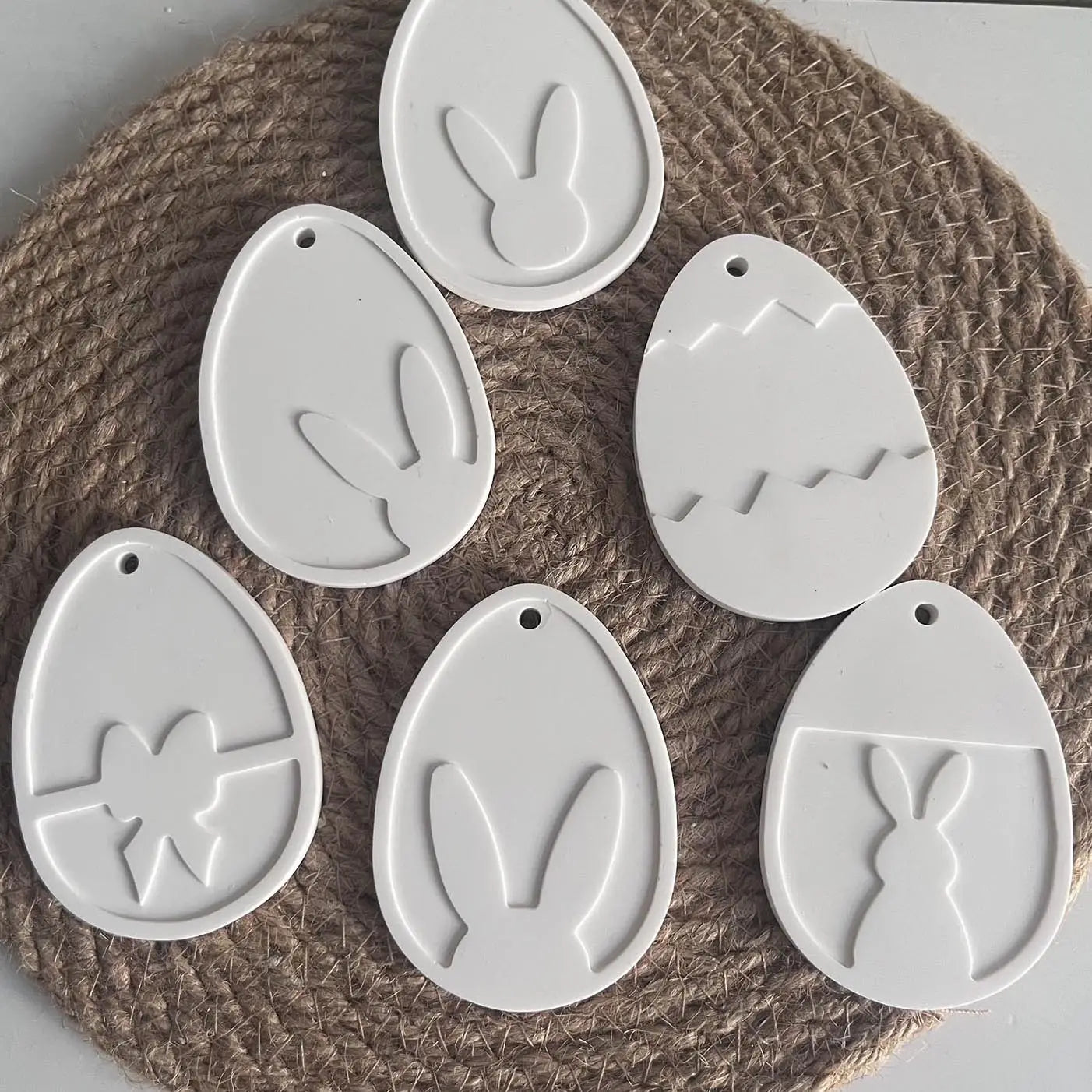 white ceramic easter egg ornaments with embossed bunny bow and cracked designs made using an easter bunny silicone resin pendant mold.