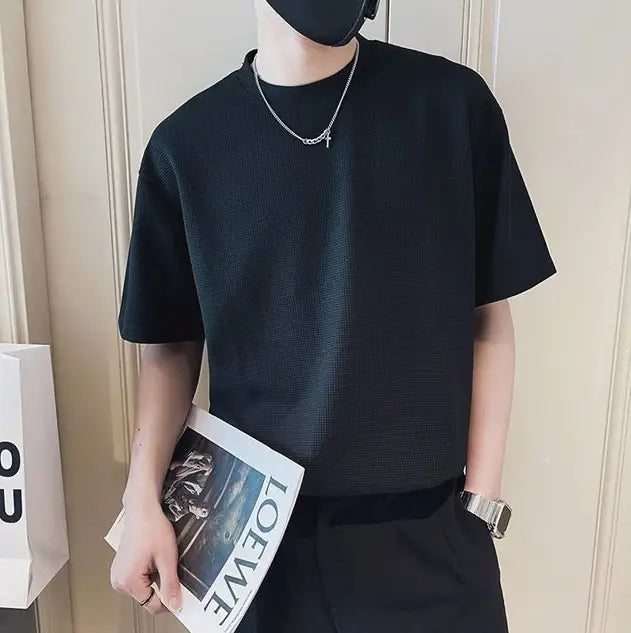T-shirt à col ras du cou en maille côtelée pour homme présentant un tissu noir texturé, manches courtes, et un design classique de col ras du cou.