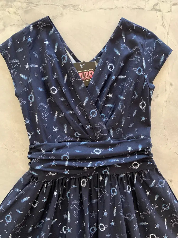 A navy blue retro-style cotton dress with v-neckline and ruched waist featuring white unicorns and stars pattern