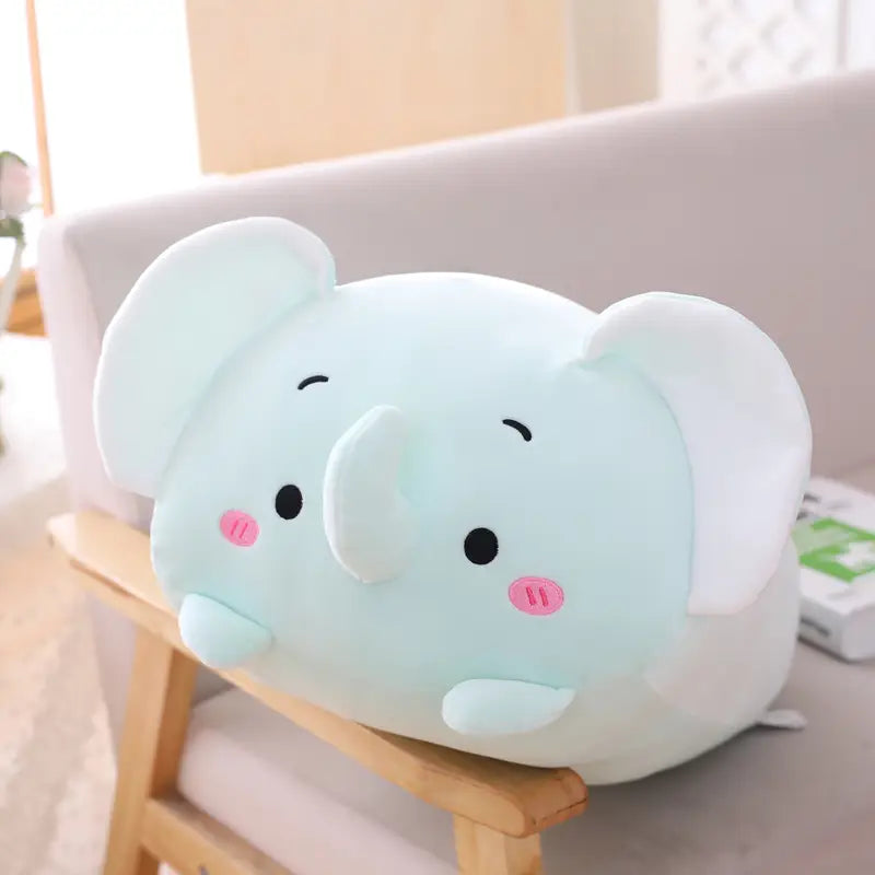 A soft, light blue plush animal pillow in the shape of an elephant with pink cheeks and black button eyes designed as a cartoon doll for kids.