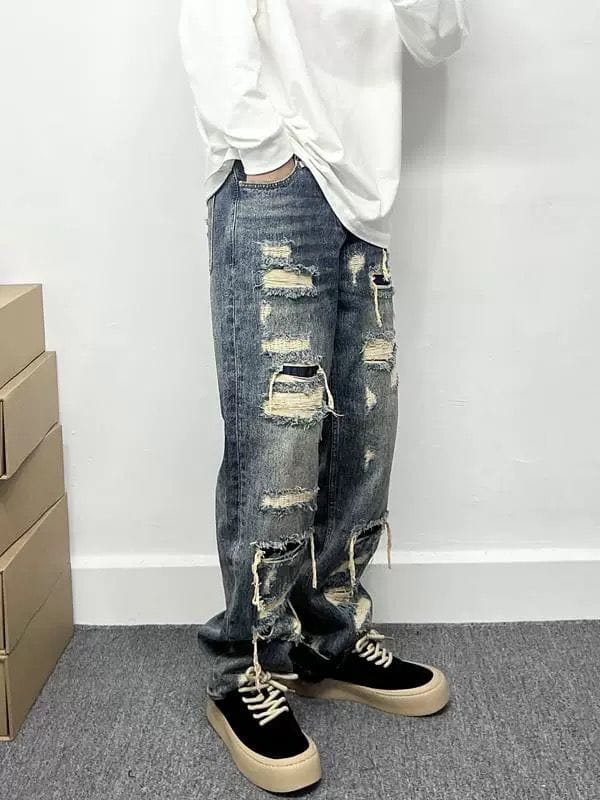 Men’s light blue distressed ripped patch denim jeans featuring multiple ripped and frayed patches along the legs.