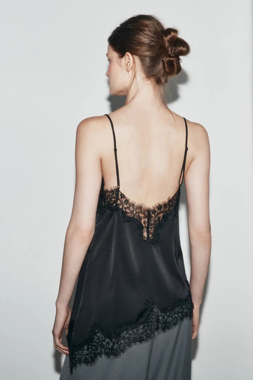 Schwarzes Satin-Camisole-Top mit zartem Spitzenbesatz entlang des Rückens und Saums, von der Rückseite aus dargestellt