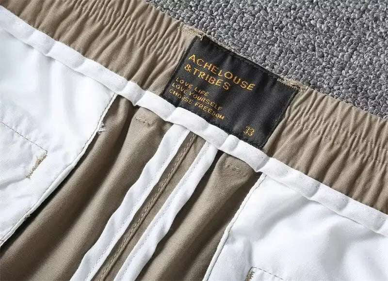 Men casual slim fit cargo shorts in khaki and white elastic waist featuring a black label with achelouse and tribes in gold lettering.