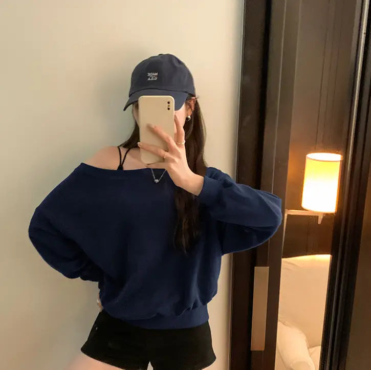 Navy blue women’s loose off shoulder ribbed knit sweater with long sleeves and ribbed cuffs.