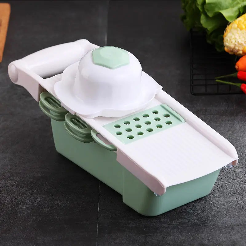 A mint green and white plastic vegetable slicer mandoline grater with a detachable grating plate and blades for efficient food preparation.