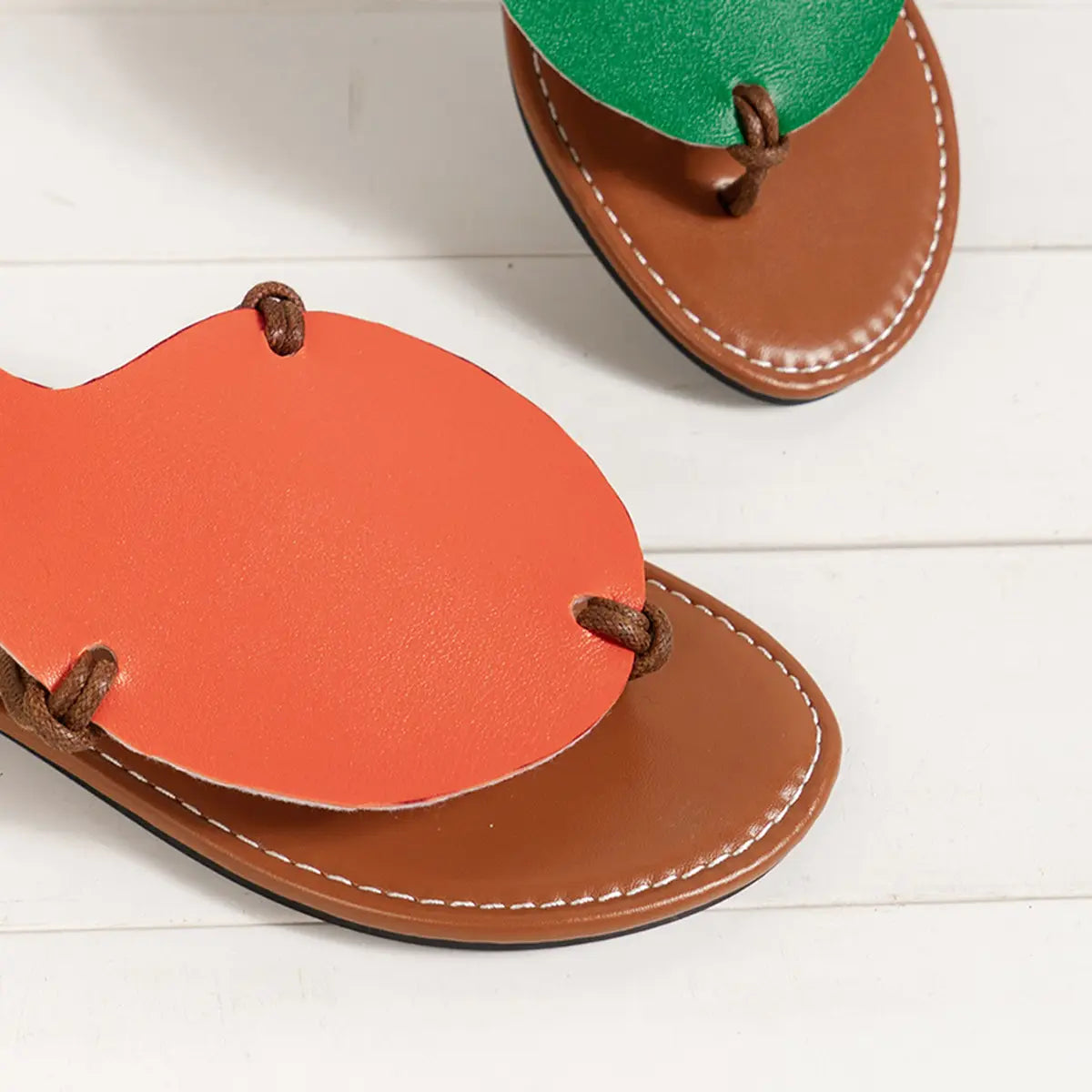 Bright orange and green leather thong sandals with brown braided straps designed as women’s leaf design casual flat flip flop sandals.