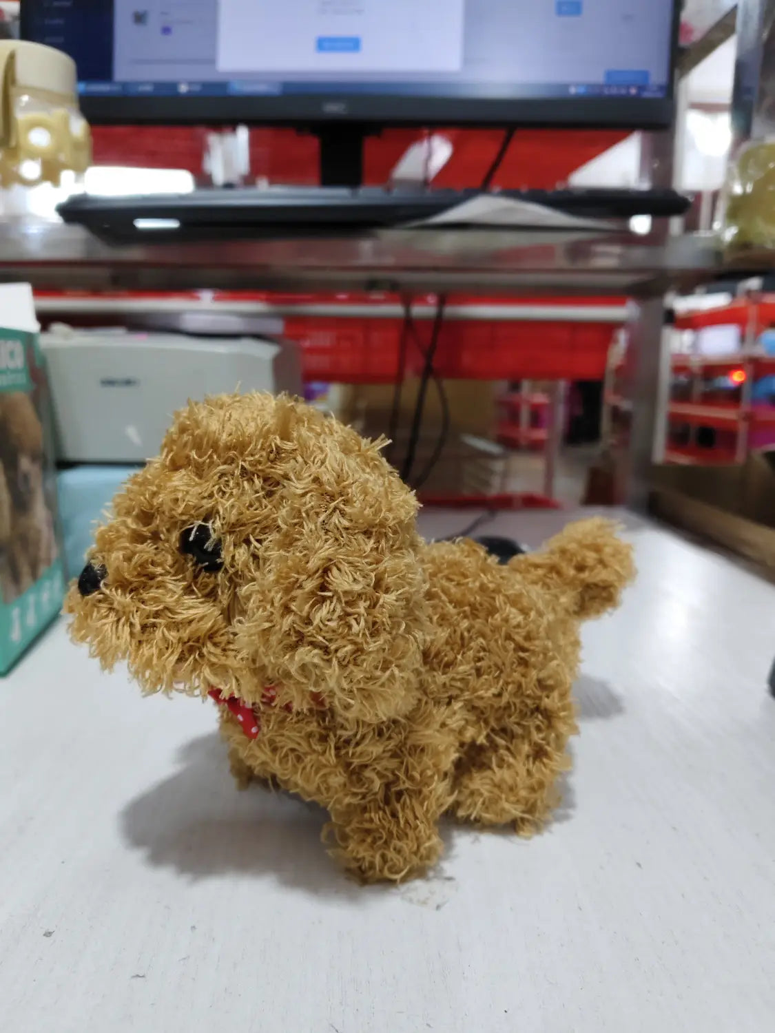 A fluffy tan interactive plush robot puppy with black button eyes and a red collar designed to produce sound and music.
