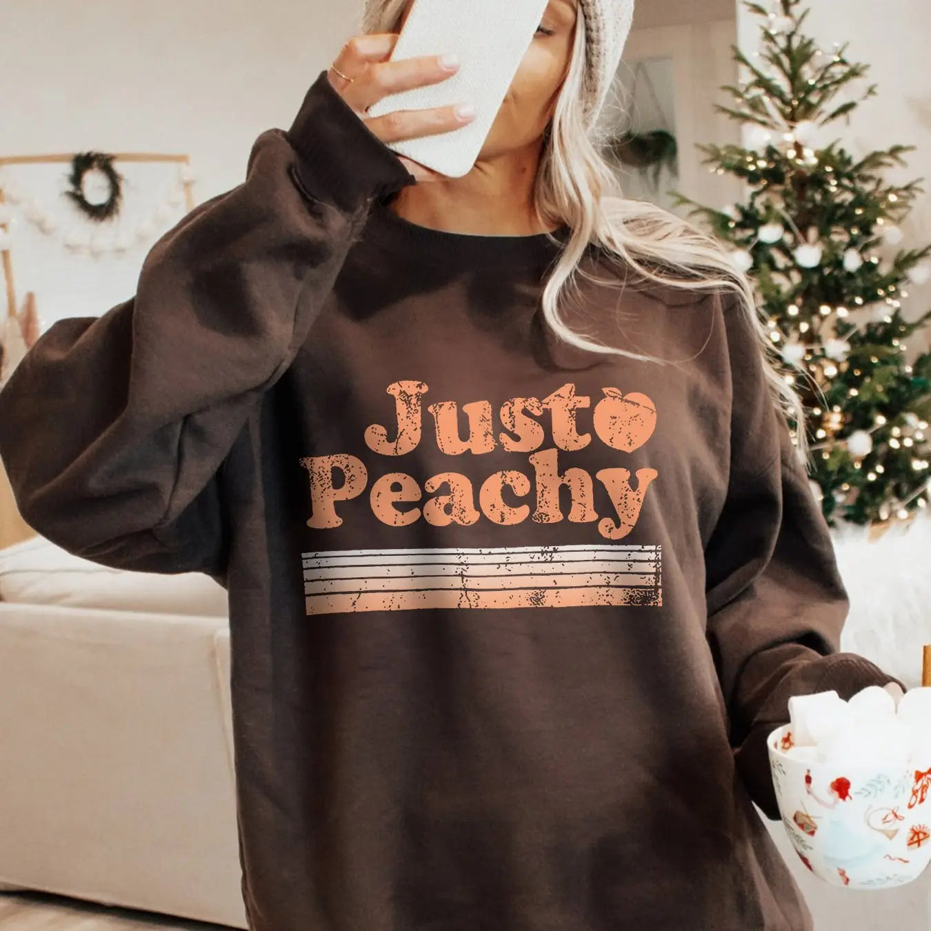 Sudadera extragrande crema de color marrón, confeccionada con material suave, con «just peachy» impreso en letras de color naranja desgastado, con franjas horizontales debajo del texto.