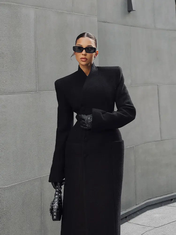 Charcoal gray wool coat for women featuring a structured design with dramatic shoulder pads and a high collar for waisted long outerwear.