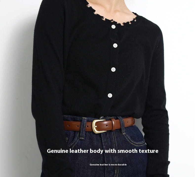 Camiseta negra de manga larga con escote deshilachado y botones blancos, mostrada junto con un cinturón reversible de cuero genuino para mujer.