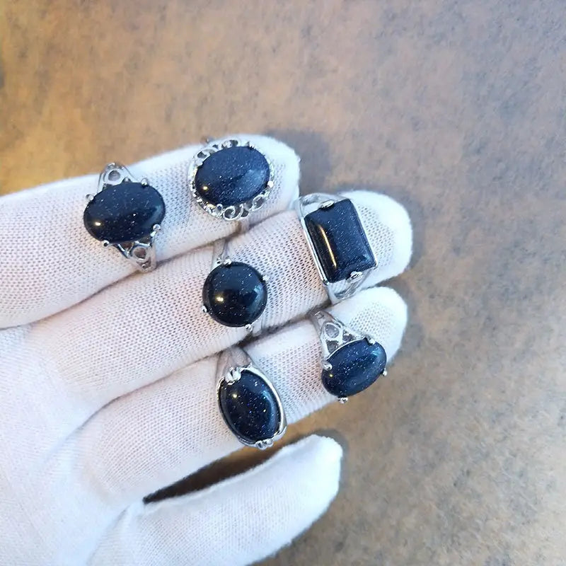 Set of five silver tone statement rings featuring deep blue glittering sandstone stones in various oval and rectangular cuts.