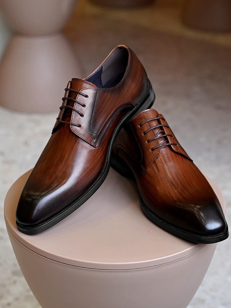 Herren-Oxfordschuhe mit eckiger Kappe aus beschichtet wirkendem Leder in poliertem Braun mit eleganten spitzen Zehen und schwarzen Gummisohlen.